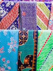 A variety of colors and motifs of batik cloth are displayed in the shop window.