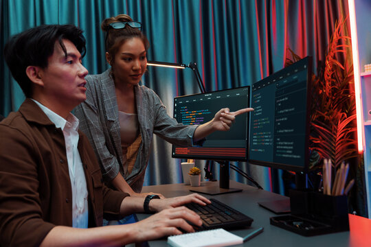 IT developers discussing with point to intelligent website development coder system running data online two screens information technology at neon light room at modern office. Infobahn.