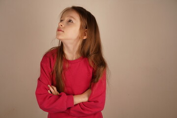 Fototapeta premium A red-haired girl stands with her arms crossed, exuding confidence and elegance. Her composed posture highlights her strong presence. The bright setting frames her striking features.