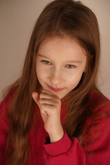 Naklejka premium Her expression conveys a sense of ease as she takes a peaceful moment. The pose highlights her serenity. The little girl rests her chin on her clenched fist, looking relaxed and calm.