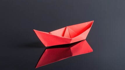 A red paper boat on a black surface.