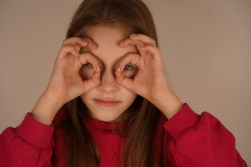 A little girl playfully forms her fingers into an 