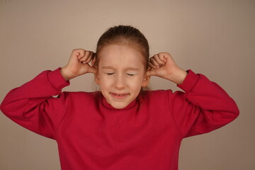 It s a moment of frustration and sensitivity to sound. The girl covers her ears with her fingers, her eyes tightly shut. Her expression shows discomfort and a desire to block out unwanted noise.