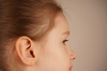 This close-up focuses on the girl's ear, capturing the fine details of her auditory structure. The...