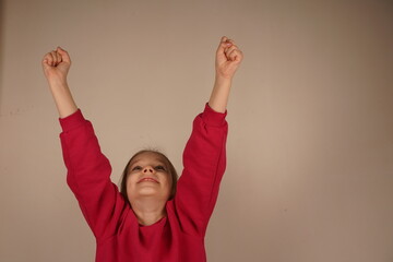 This moment captures her pure enthusiasm and excitement. The little girl raises her fists high in...