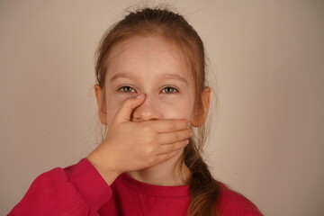 A genuine and tender depiction of fear. A frightened girl with a ponytail places her hand over her...