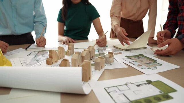 Smart architect and safety engineer discussion about building blueprint on table with architectural document, measurement tools and wooden block scatter around at modern office. Closeup. Delineation.