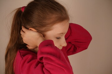 A redhead girl in a red hoodie covers her ears with her hands, blocking out the surrounding noise....