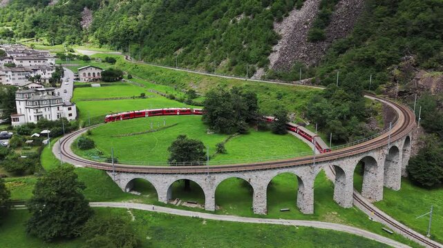 Aerial view of a Bernina Express train crossing the Brusio spiral viaduct of Rhaetian Railway, Grisons canton, Switzerland