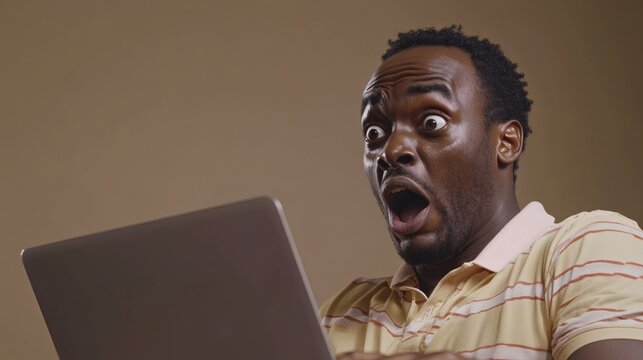 A surprised man looking at his laptop screen with open mouth