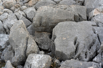 Detailed view of rugged gray rock formations with deep fissures and rough surfaces in mountainous environment. Concept of geology, natural erosion, and wilderness.