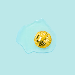 Creative concept with shiny disco ball and raw egg on blue background. MInimal party cooking flat lay.
