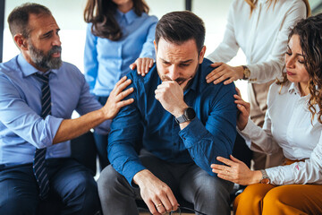 Supportive Group Consoling a Distressed Man in a Professional Setting