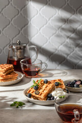 Waffles with fresh blueberries and cream in bright morning light. Healthy food, breakfast. Waffles with berries, text space.
