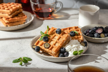 Waffles with fresh blueberries and cream in bright morning light. Healthy food, breakfast. Waffles with berries.
