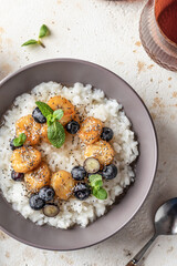 Rice porridge with banana, blueberries, chia seeds and honey sauce on a table close up, hot and healthy breakfast