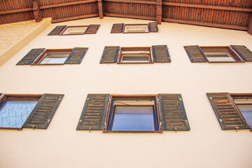 Facade of a building with multiple windows and wooden shutters viewed from below. Symmetrical...