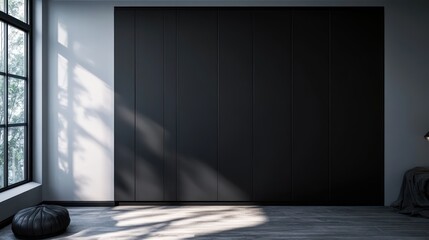 A dark matte black wardrobe with smooth closed doors, against a light gray wall in a modern minimalist bedroom