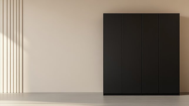 A matte black wardrobe with sleek closed doors standing against a minimalist beige wall in the modern interior of a minimal home
