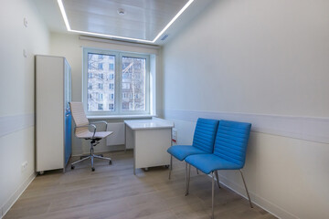 A doctor's office with cupboards, a table and chairs, in an outpatient clinic.