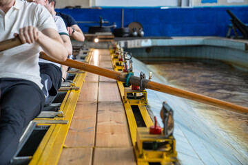 Water sports rowing simulator. Closeup rowing team hands work with paddles, preparing for competitions. Arms make circular motions developing flexibility stability, muscle memory and concentration
