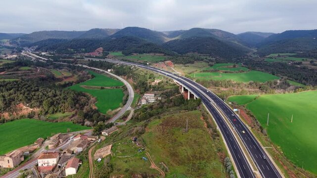 Toma a&eacute;rea de una autopista moderna que cruza un valle verde con monta&ntilde;as al fondo. El movimiento del dron es un ascenso leve, revelando el entorno natural y la infraestructura vial.