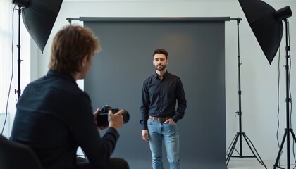Photographer takes portrait of man in photo studio. Employee stands against gray backdrop. Pro headshot session, corporate portraits against sleek background. Photo studio lighting equipment. Digital