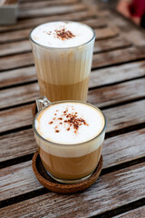 Rustic Latte Duo on Wooden Table
Two lattes in transparent glasses with frothy milk and cocoa powder, placed on a rustic wooden surface. A cozy and artistic coffee moment captured.