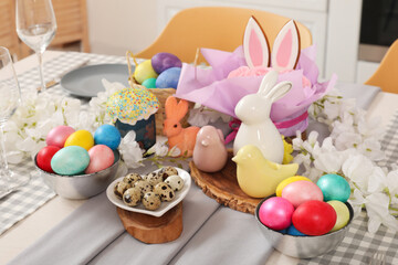 Festive table setting with flowers, Easter bunny and painted eggs