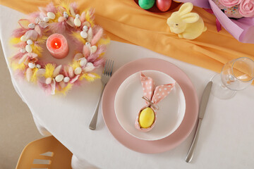Festive table serving with painted egg in folded napkin for Easter celebration, closeup