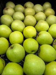Fresh green apples neatly arranged in a market display. Their bright color and smooth texture highlight their crispness and freshness.
