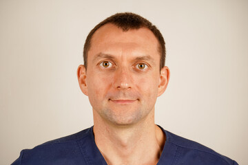 Obraz premium In dark blue medical clothing, the man poses for a detailed photo. His focused gaze radiates professionalism and authority. The image emphasizes care, commitment, and expertise.