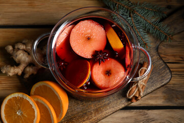 Glass cooking pot of hot mulled wine with apple and orange on wooden background