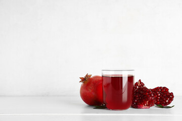 Glass of fresh pomegranate juice and fruits on white wooden table