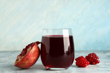 Glass of fresh pomegranate juice on light blue background