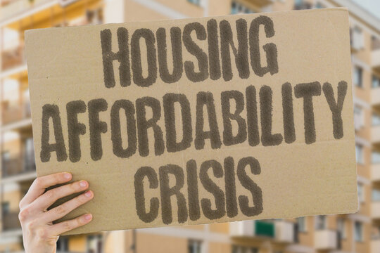 "Housing affordability crisis" on worn cardboard. Highlights the difficulty of affording homes in cities. RENTS. MORTGAGES. SUPPLY. DEMAND. CONSTRUCTION. DEVELOPMENT. INFLATION. ZONING