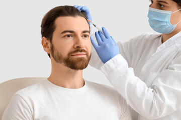 Female trichologist giving man injection for hair growth in clinic