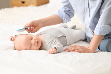 Mother brushing her sleeping little baby's head with cradle cap on bed, closeup