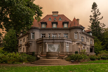 Pittock Mansion in Portland, Oregon, under an orange-tinted sky caused by thick wildfire smoke from the devastating 2020 fires, highlighting environmental disaster effects