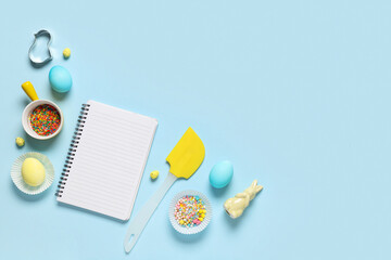 Composition with blank notebook for recipes, Easter eggs, colorful sprinkles and baking tools on...