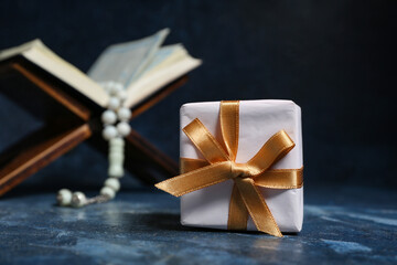 Koran, tasbih and gift box on blue grunge background. Ramadan celebration