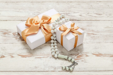 Tasbih and gift boxes on white wooden background. Ramadan celebration