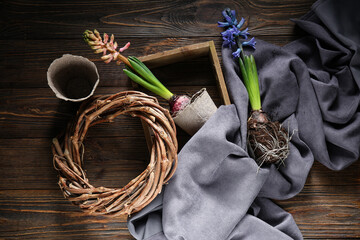 Hyacinth plants with peat pots and wreath on wooden background