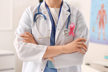 Female doctor with pink ribbon in clinic, closeup. Breast cancer awareness concept
