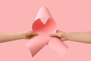 Hands with pink ribbon on color background. Cancer awareness concept