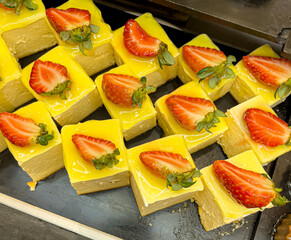Yellow lemon cake with fresh strawberries and mint on a tray, close-up