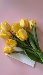 Blank white card surrounded by fresh, beautiful yellow tulips on a pale pink background