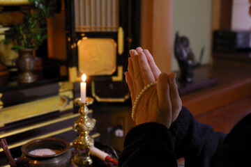 仏壇で供養をする高齢女性