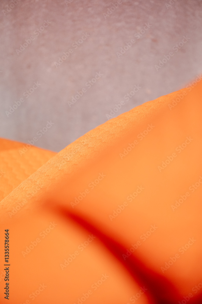 Poster orange fabric with soft shadows and a neutral background creates a calming minimalist visual