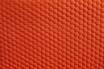 Close up of a vibrant orange fabric featuring a textured honeycomb pattern creating a visually...